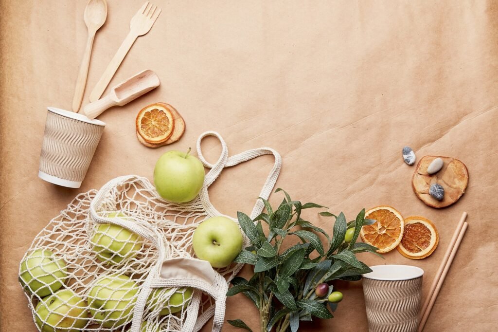 Natural craft paper background complete wooden cutlery, cardboard cups, apples and dry oranges.